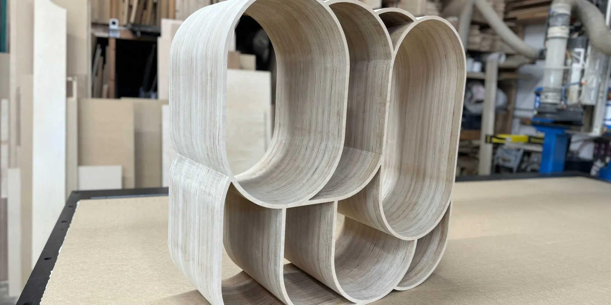 Stack-laminated plywood form with curved openings, CNC-routed, on the router bed