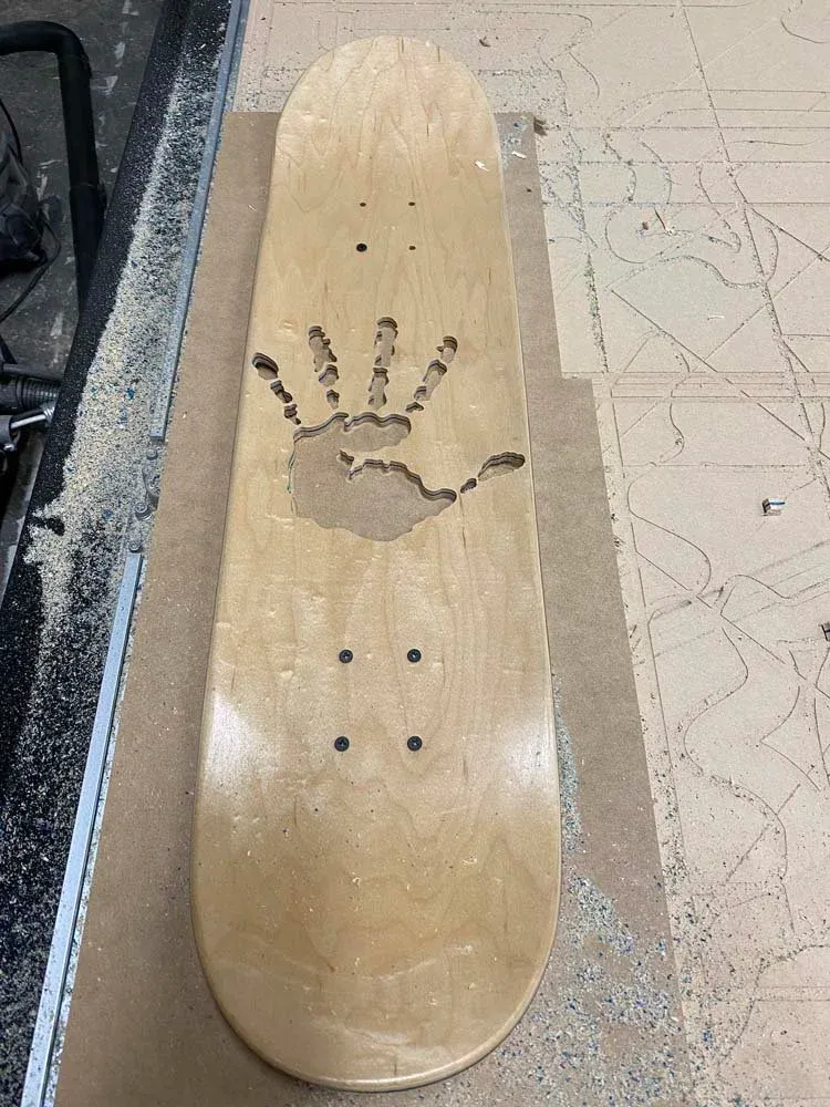 Skateboard deck with the artist's hand silhouette CNC-milled through