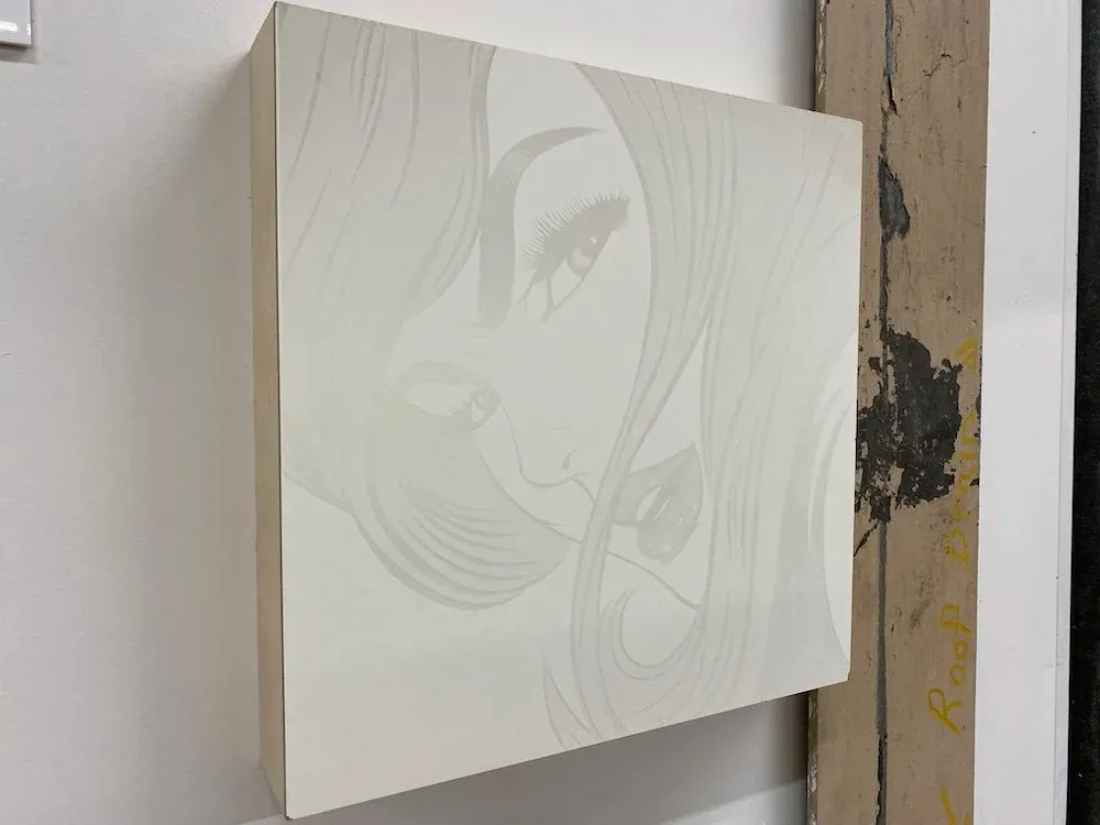 Halftone laser-etched portrait of a woman on white clay board