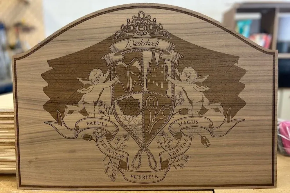 Walnut plywood laser-engraved with a heraldic crest, cherubs, and a crown